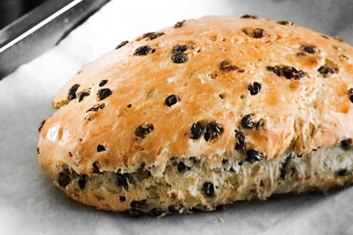 Een versgebakken paasbrood op een stuk bakpapier.