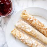 Opgerolde pannenkoeken op een bord met jam.