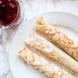 Opgerolde pannenkoeken op een bord met jam.