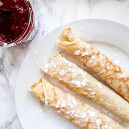 Opgerolde pannenkoeken op een bord met jam.