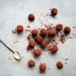 Chocolade karamel truffels op een grijze achtergrond en een lepel.