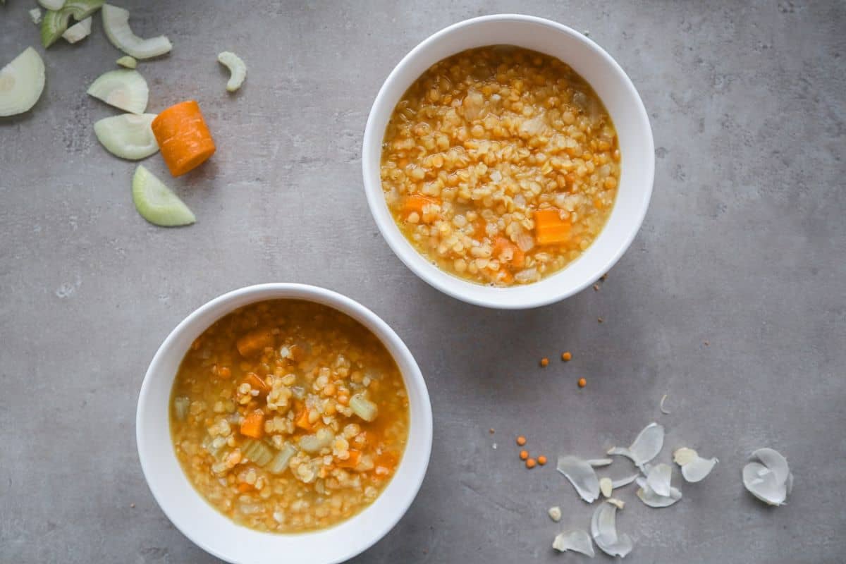 Twee witte kommen met linzensoep van rode linzen.