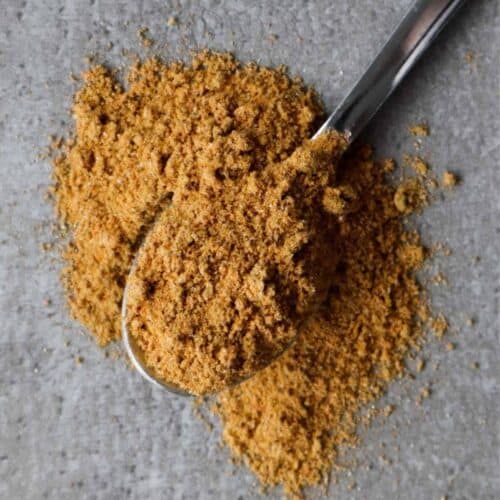 Nasi kruiden op een lepel en een grijze achtergrond.