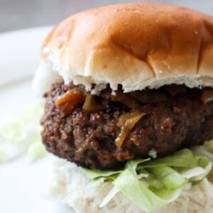 Een hamburger op een broodje met sla en uitjes.