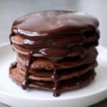 Chocoladepannenkoeken met chocoladesaus op een wit bord.