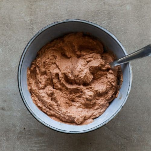 een overhead shot van chocolade slagroom in een blauwe kom en een lepel