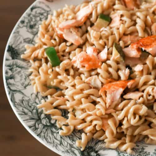 Een close up van stukjes pasta en gebakken zalm met alfredo saus
