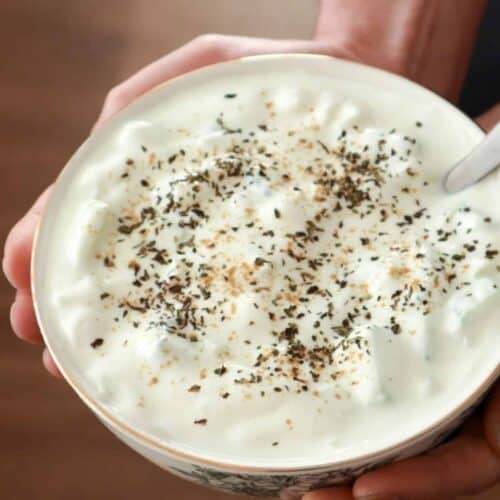 Een close up van raita saus in een schaal met een bruine achtergrond