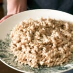 Handen die een bord met pasta vast houden