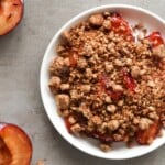Een overhead shot van pruimen crumble op een wit bord